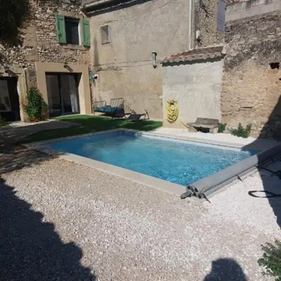 a swimming pool in a yard next to a building at La maison d'Antoine à Robion in Robion en Luberon