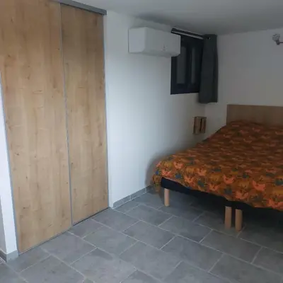 a bedroom with a bed and a wooden closet at La maison d'Antoine à Robion in Robion en Luberon