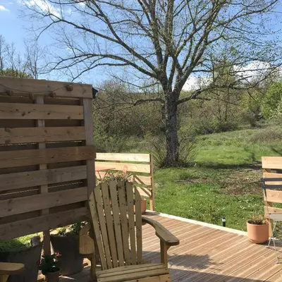 a wooden chair sitting on a deck next to a tree at Le Mas de Loume in Sault-de-Vaucluse