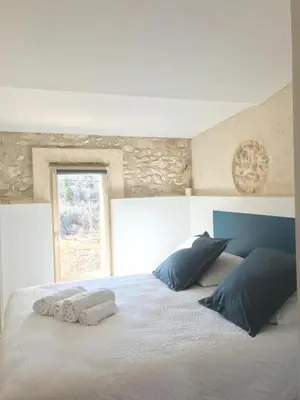 a bedroom with a white bed with pillows and a window at Le Mas de Loume in Sault-de-Vaucluse