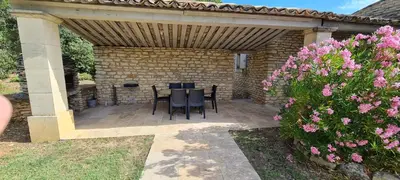 a patio with a table and chairs under a wooden pergola at Villa Trempadou in Gordes