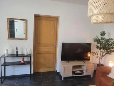 a living room with a flat screen tv next to a door at Appartement cosy avec exterieur au coeur de la Provence in Monteux
