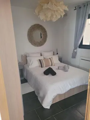 a bedroom with a bed with white sheets and a mirror at Appartement cosy avec exterieur au coeur de la Provence in Monteux
