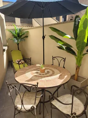 a table with chairs and an umbrella on a patio at Appartement cosy avec exterieur au coeur de la Provence in Monteux