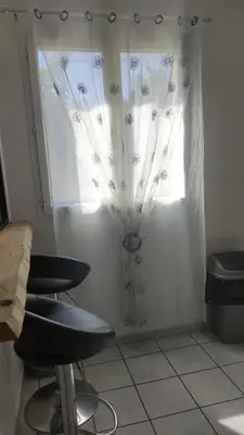 a room with a window with curtains and a chair at L'Appart in Cheval-Blanc