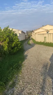 a gravel road next to a fence and a building at L'Appart in Cheval-Blanc