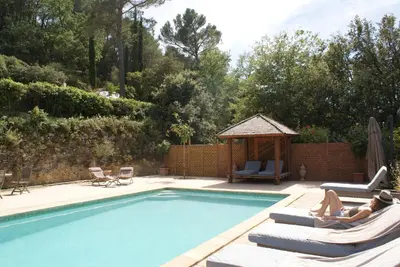 two people laying on lounge chairs next to a swimming pool at L'Irisciabella in Lourmarin