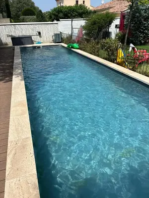 a swimming pool with blue water in a yard at A l'ombre des oliviers in LʼIsle-sur-la-Sorgue