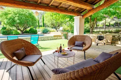 a patio with wicker chairs and a table on a deck at Villa Les Alpilles by Villa Plus in Mouriès