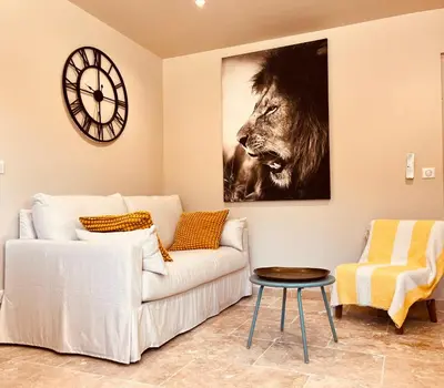 a living room with a couch and a clock on the wall at Évasion charme et jacuzzi en pleine nature in Grans