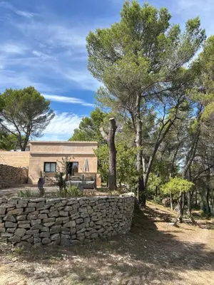 a stone retaining wall in front of a stone house at Gîte en Provence pour amoureux de la nature in Rognes