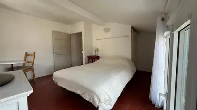 a bedroom with a white bed and a table at Charmante petite maison à Murs in Murs