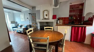 a kitchen and living room with a wooden table and chairs at Charmante petite maison à Murs in Murs