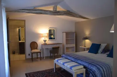 a bedroom with a bed and a desk and a table at Moulin des Gypses Gîte Les Pampres, Ventoux in Mormoiron