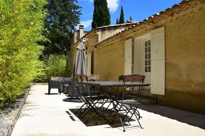 a patio with a table and chairs and an umbrella at Moulin des Gypses Gîte l'Oliveraie, Ventoux in Mormoiron