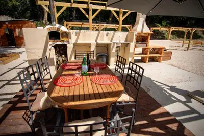 a wooden table with chairs and an umbrella at Appartement charmant près du centre d'Avignon, 60m², piscine in Avignon