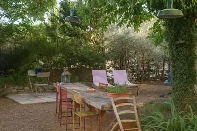 a wooden table and chairs in a garden at Le Cabanon Provençal Traditionnel Jardin Barbecue & Cheminée in Saumane-de-Vaucluse