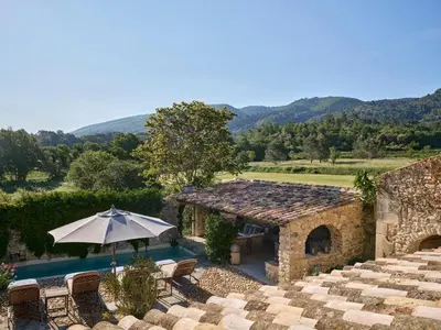 an outdoor patio with an umbrella and a pool at Villa Syrah, La Bastide de Marie, Villa avec services in Ménerbes