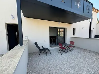 a patio with chairs and a table on the side of a building at Appartement neuf centre du village in Le Puy-Sainte-Réparade