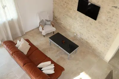 a living room with a couch and a tv and a chair at Les Vignes du Luberon in Saignon
