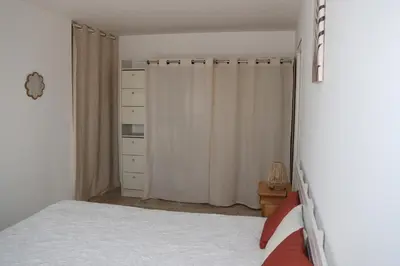 a bedroom with white curtains and a bed and a dresser at Les Vignes du Luberon in Saignon