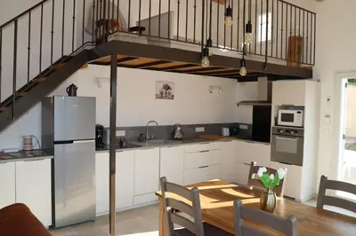 a kitchen with a dining table and a staircase at Les Vignes du Luberon in Saignon