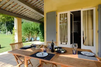 a wooden table with plates and wine glasses on a patio at Villa-Provence-Pont-Royal in Mallemort