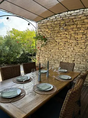 a wooden table with plates and glasses on it at Le Bastidon des Mésanges in Gordes