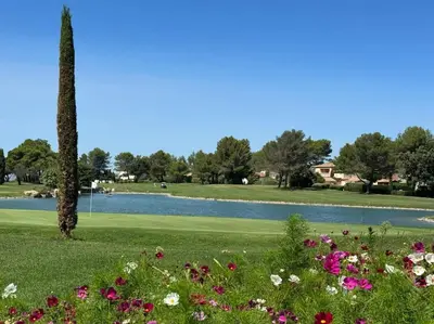 a park with a lake and flowers in the grass at Maison haut de gamme dans le golf de pont royal in Mallemort