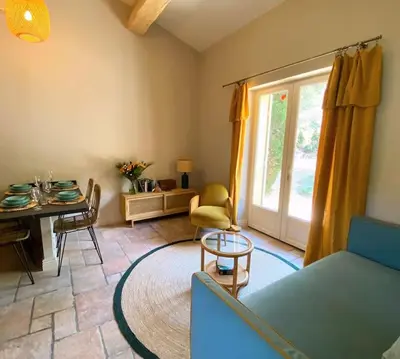 a living room with a couch and a table and a window at Mazet Rigodon Alpilles in Eygalières