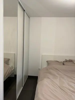 a white bedroom with a bed and a mirror at Appartement T2 climatisé garage in Aix-en-Provence