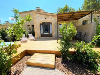 a backyard with a wooden deck and a house at Mazet Cordelles Alpilles in Eygalières