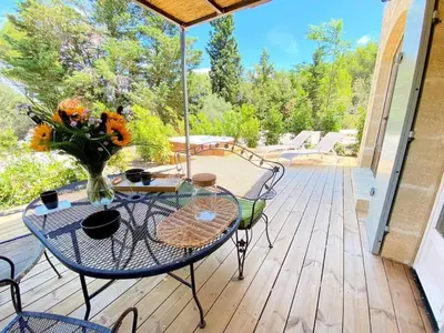 a patio with a table with a vase of flowers at Mazet Cordelles Alpilles in Eygalières