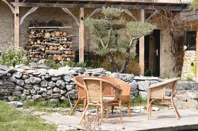 two chairs and a table in front of a stone wall at Ecolieu Silenciane in Simiane-la-Rotonde