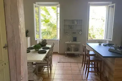 a kitchen with a table and chairs and two windows at Limasola - Apartment and its rooftop in Les Vignères
