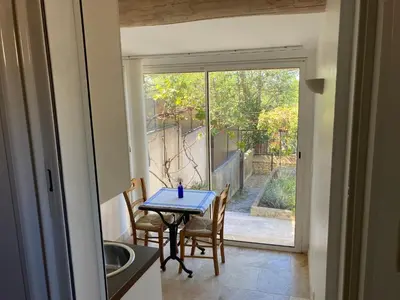 a table and chairs in a kitchen with a sliding glass door at Le gîte sous les pins in Les Taillades