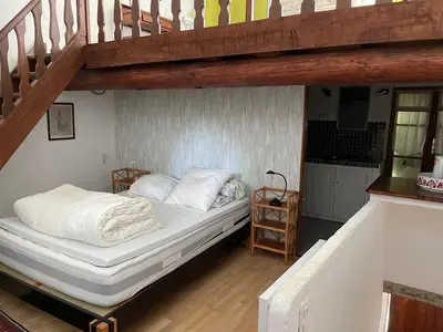 a bedroom with a bed under a wooden staircase at La Magnanerie in Cabrières-dʼAvignon