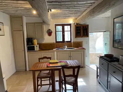 a kitchen with a wooden table and chairs in a room at La Magnanerie in Cabrières-dʼAvignon