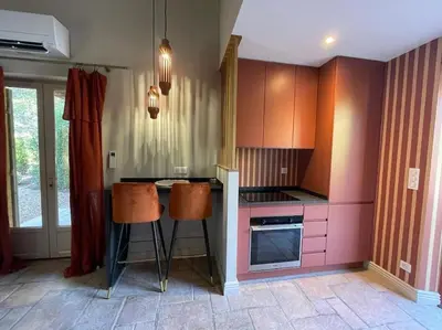 a kitchen with pink cabinets and two bar stools at Domaine Farandole in Eygalières