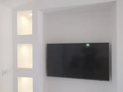 a flat screen tv on a white wall with two pictures at 2 Voyageurs - 1 Lit - Proche de toutes commodités in Peyrolles-en-Provence
