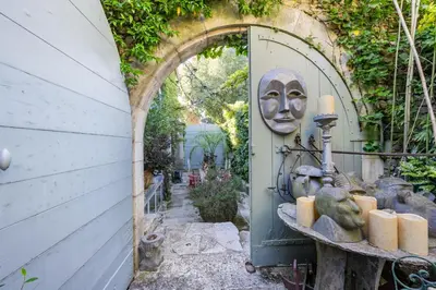 an entrance to a garden with an archway and candles at La maison de la piscine in Goult