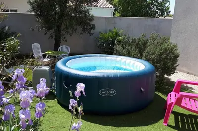 a blue pool in a garden with purple flowers at Nice flat with jacuzzi and garden in Velleron