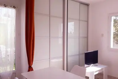 a white room with a white table and a television at Nice flat with jacuzzi and garden in Velleron