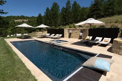 a swimming pool with chairs and umbrellas in a yard at Domaine de la Lisière in Sault-de-Vaucluse