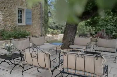 a patio with chairs and tables and a tree at Domaine de la Lisière in Sault-de-Vaucluse