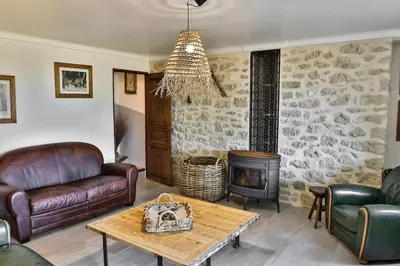 a living room with leather furniture and a wood stove at sous la glycine de costebelle in Cheval-Blanc