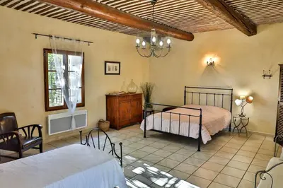a bedroom with two beds and a table and chairs at sous la glycine de costebelle in Cheval-Blanc