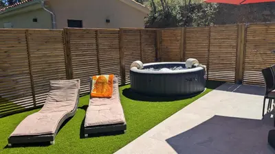 a garden with a hot tub and two chairs on the grass at Studio climatisé - Terrasse, Plancha, Fibre in Aix-en-Provence