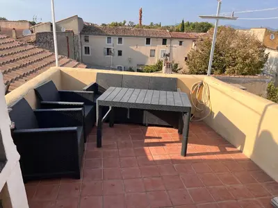 a patio with a bench and chairs on a balcony at Maison de ville avec rooftop vue sur le Ventoux in Monteux