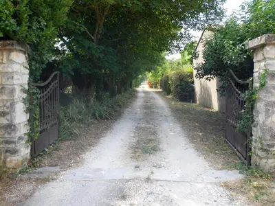 a dirt road with a iron fence and trees at le gîte Lou Jas in Eyragues